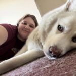 female laying next to a large white dog